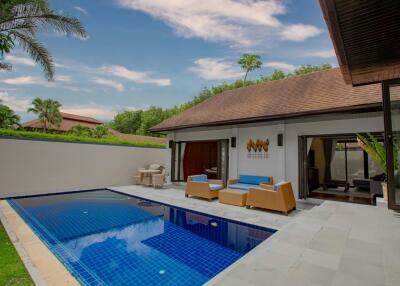 Luxurious residential outdoor pool with adjacent lounge area and modern villa