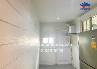 Brightly lit hallway with white walls and a door exiting the building
