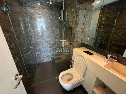 Modern bathroom with marble walls, glass shower enclosure, and contemporary fixtures