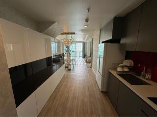 Modern kitchen with integrated living space featuring wooden flooring and elegant lighting