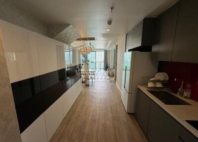 Modern kitchen with integrated living space featuring wooden flooring and elegant lighting