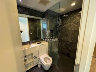 Modern bathroom with glass shower enclosure and elegant dark marble walls