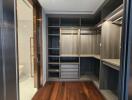 Spacious walk-in closet with custom shelving and wooden flooring