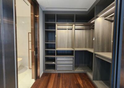 Spacious walk-in closet with custom shelving and wooden flooring