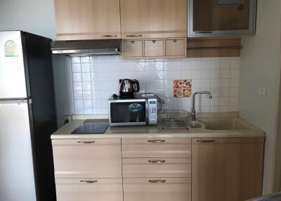 Compact modern kitchen with light wood cabinetry and white appliances