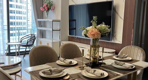 Elegant dining area within a modern living room featuring a large flat-screen TV and city view