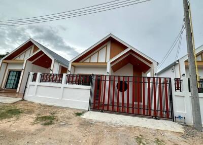 Modern single-family home with a red and white facade and gated entrance