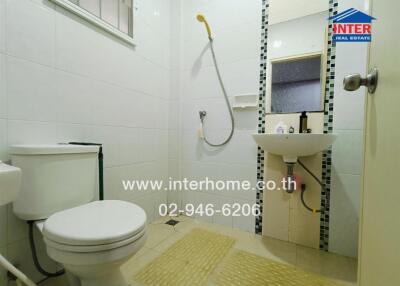 Compact white bathroom with shower, toilet, and sink