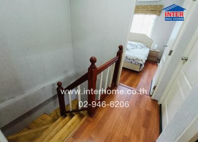 View of a home hallway leading to a bedroom with wooden floors