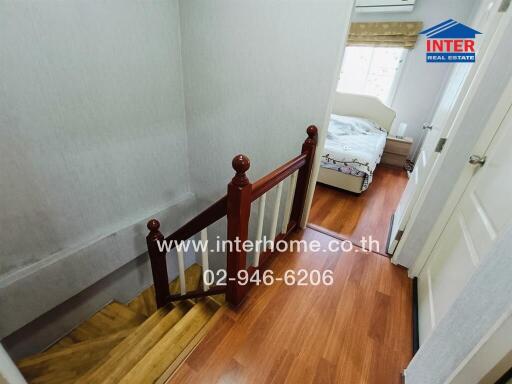 View of a home hallway leading to a bedroom with wooden floors