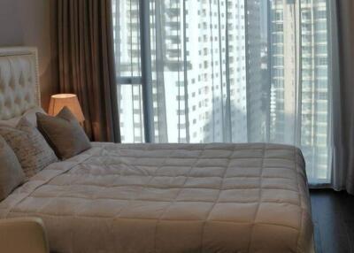 Modern bedroom with large bed and city view through curtains