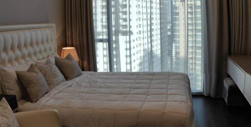 Modern bedroom with large bed and city view through curtains