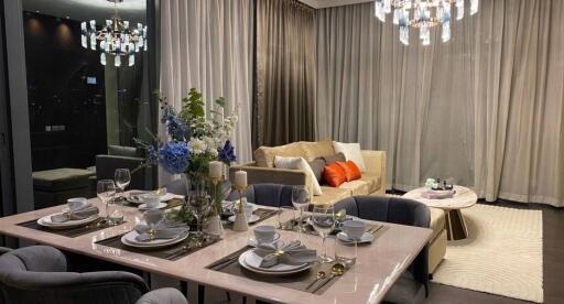 Elegant dining area with table set for dinner and adjacent cozy living space