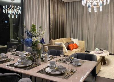 Elegant dining area with table set for dinner and adjacent cozy living space