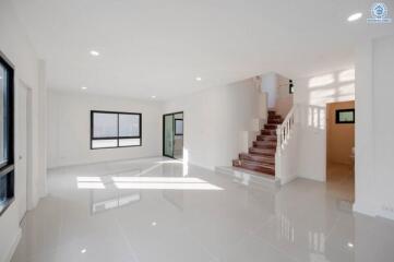 Spacious and bright living room with staircase and multiple windows