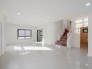 Spacious and bright living room with staircase and multiple windows