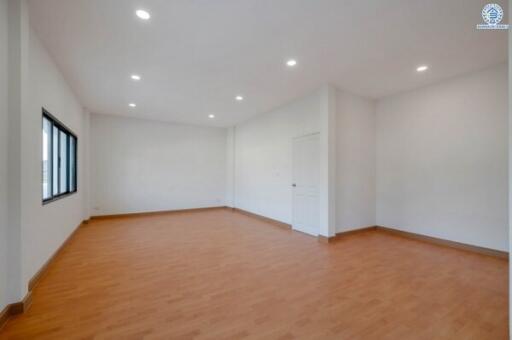 Spacious empty bedroom with wooden flooring and white walls