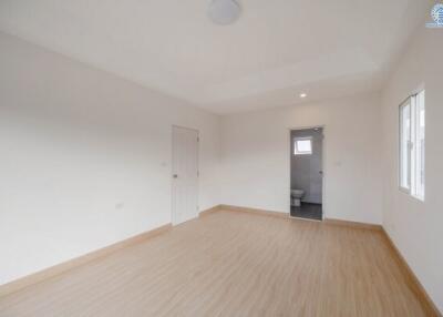 Spacious and bright empty bedroom with hardwood floors and multiple windows