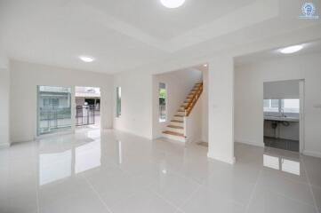 Spacious and bright living room with tiled flooring and easy access to staircase