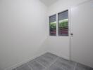 Small room with grey tiled floor and white walls