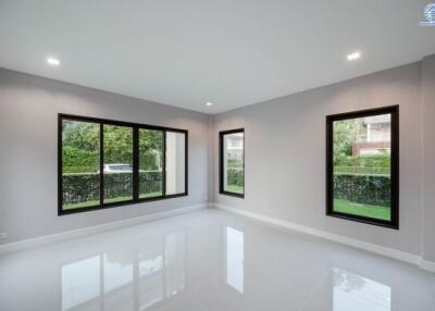 Spacious and well-lit living room with large windows and glossy tiled flooring