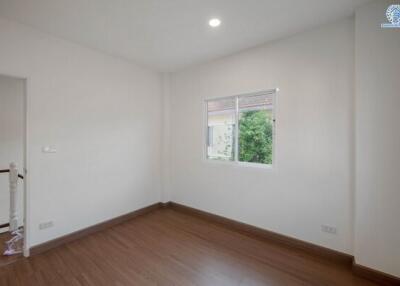 Spacious empty bedroom with wooden flooring and large window