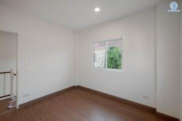 Spacious empty bedroom with wooden flooring and large window