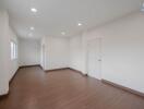 Spacious empty living room with wooden floors and white walls