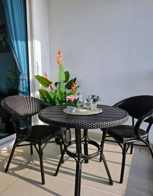 Bright and inviting balcony area with a round table and chairs, surrounded by vibrant plants