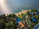Aerial view of a luxury beachfront resort with swimming pools and lush gardens