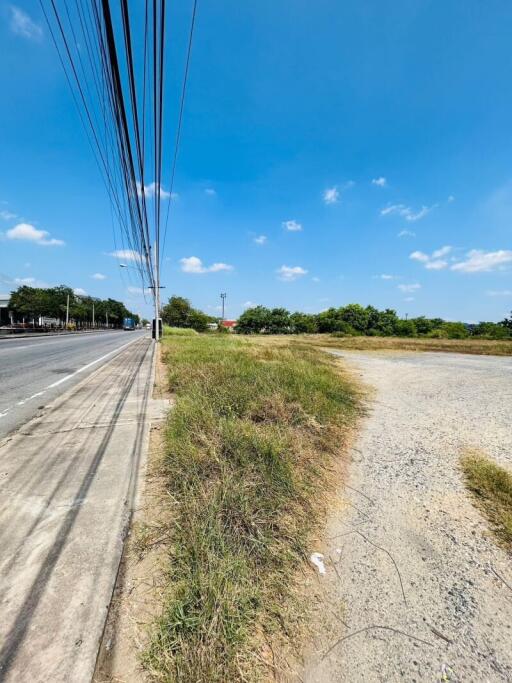 Vacant land next to a paved road under clear blue sky