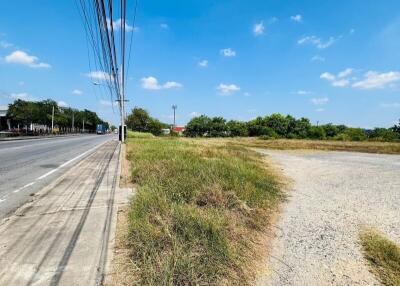 Vacant land next to a paved road under clear blue sky