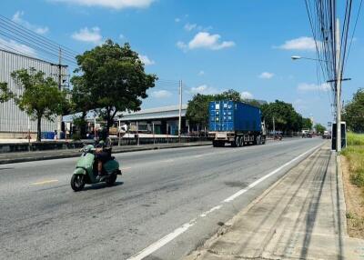 View of a busy street from the sidewalk showing vehicles and clear blue sky