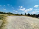 Expansive outdoor vacant lot with clear blue sky and scattered clouds