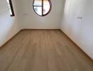 Empty bedroom with wooden flooring and a circular window