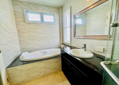 Spacious modern bathroom with natural stone tiles and large bathtub