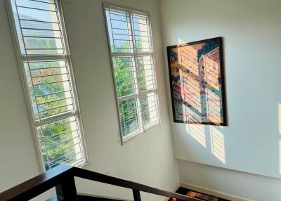 Bright staircase landing with large windows and art decor