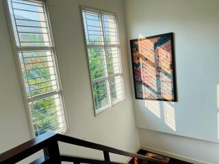 Bright staircase landing with large windows and art decor