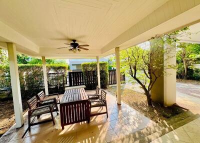 Spacious covered patio with wooden furniture and garden view