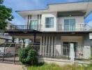 Modern two-story residential house with balcony and landscaped front yard