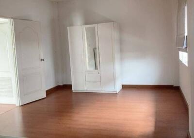 Spacious bedroom with wooden floors and large white wardrobe