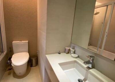 Modern bathroom interior with neat design featuring a large mirror, sink, and toilet