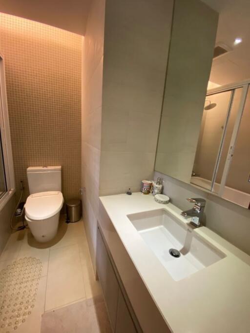 Modern bathroom interior with neat design featuring a large mirror, sink, and toilet