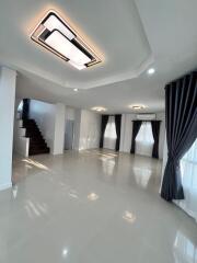 Spacious and elegantly designed living room with polished tile flooring, sophisticated lighting, and a grand staircase