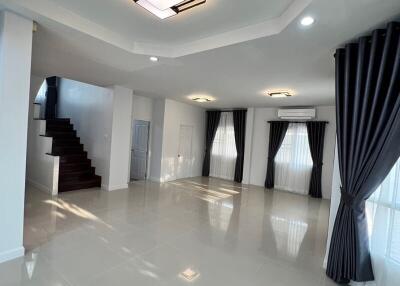 Spacious and elegantly designed living room with polished tile flooring, sophisticated lighting, and a grand staircase
