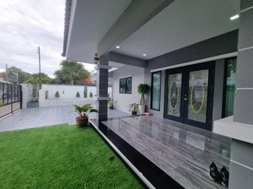 Modern home exterior with lush green lawn and stylish grey tiles