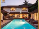 Luxurious poolside view of a grand two-storey home at dusk