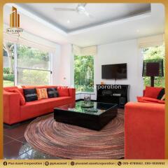 Spacious and brightly lit living room with vibrant orange sofas and large windows