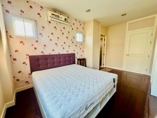 Bright and well-furnished bedroom with floral wallpaper and wooden flooring