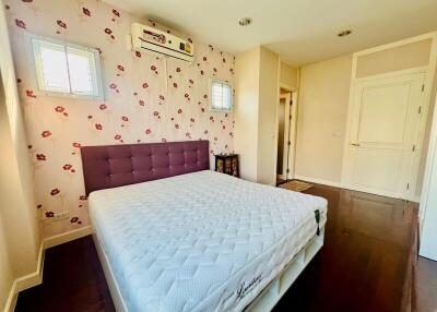 Bright and well-furnished bedroom with floral wallpaper and wooden flooring